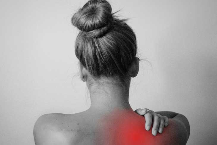 肩の痛みで腕を押さえる女性のイメージ